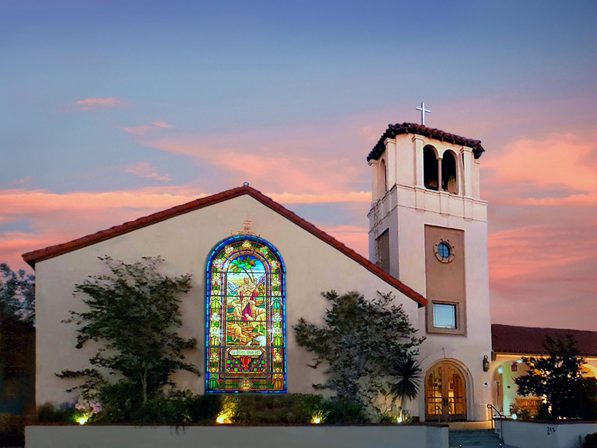 Image of church exterior, with a prominent stained glass window, taken at sunrise